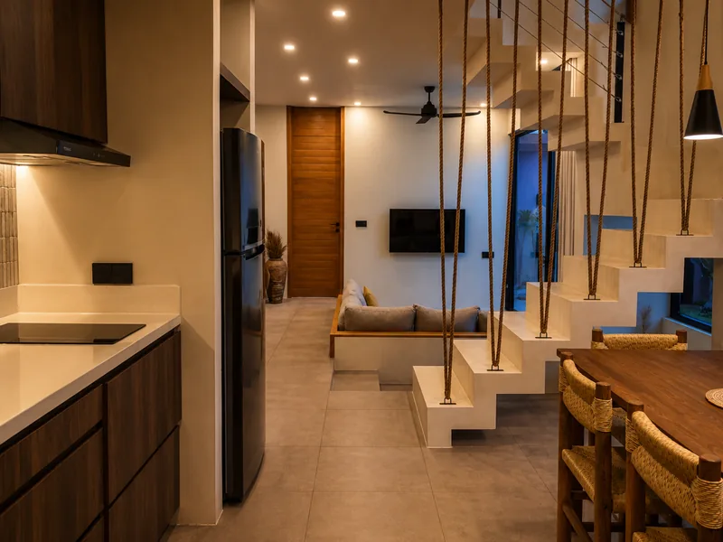The Five Villas: salón y cocina abiertos con escalera de madera